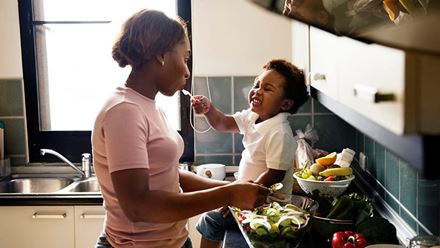 Child feeding mother in the kitchen Dietary Recommendations for Healthy Children
