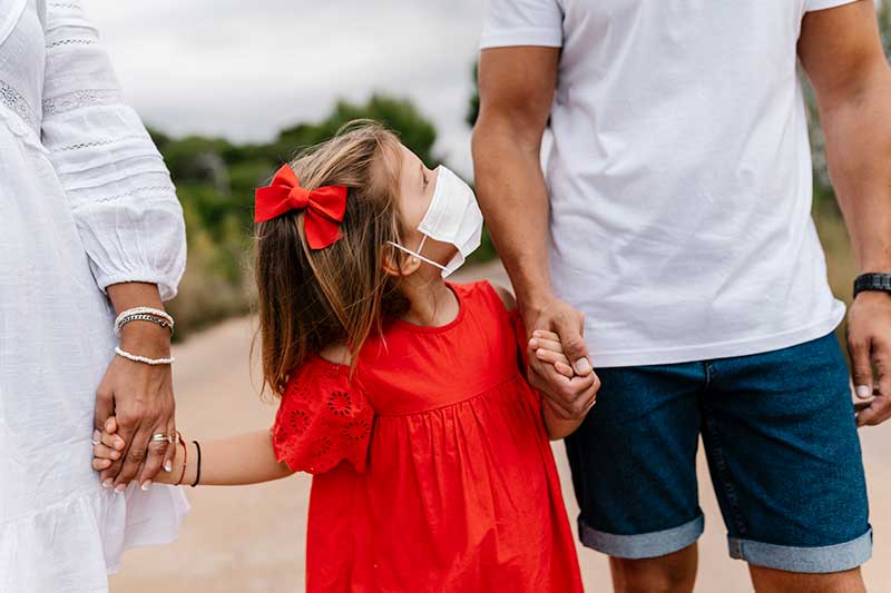 Family holding hands walking in masks