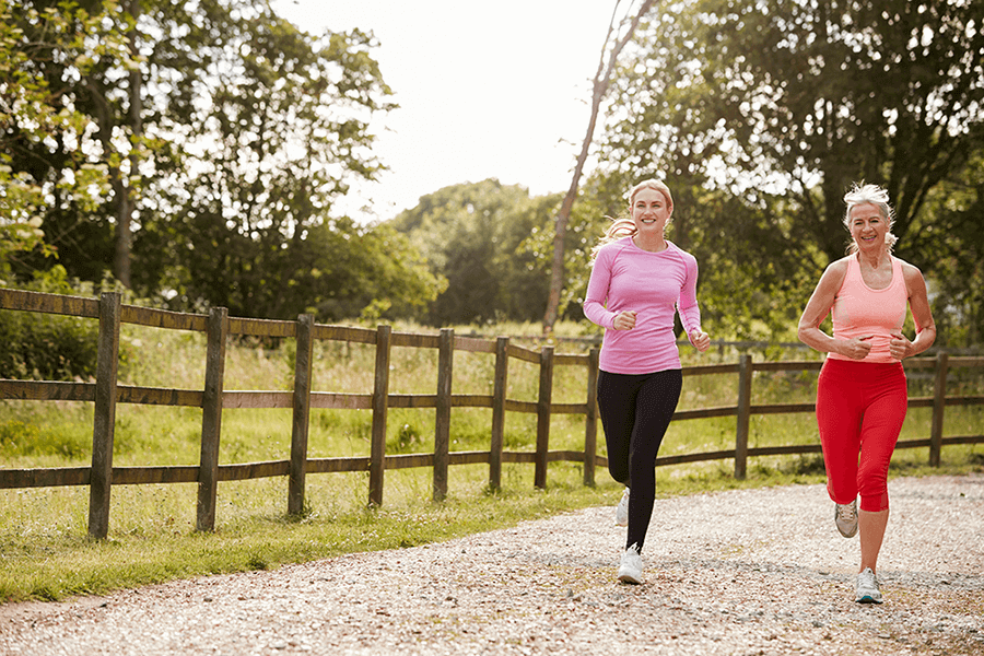 young and senior women enjoying run through countryside together