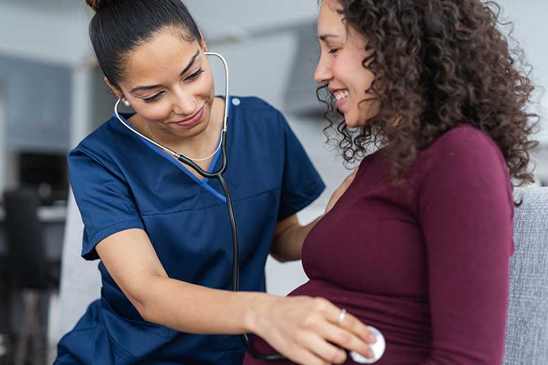 médico con estetoscopio en la barriga de una mamá embarazada