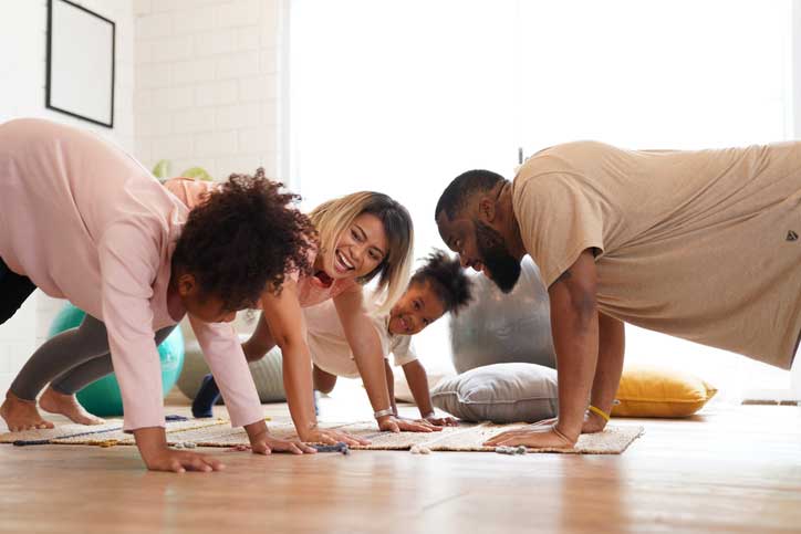 Familia alegre riendo mientras hacen ejercicio en una habitación