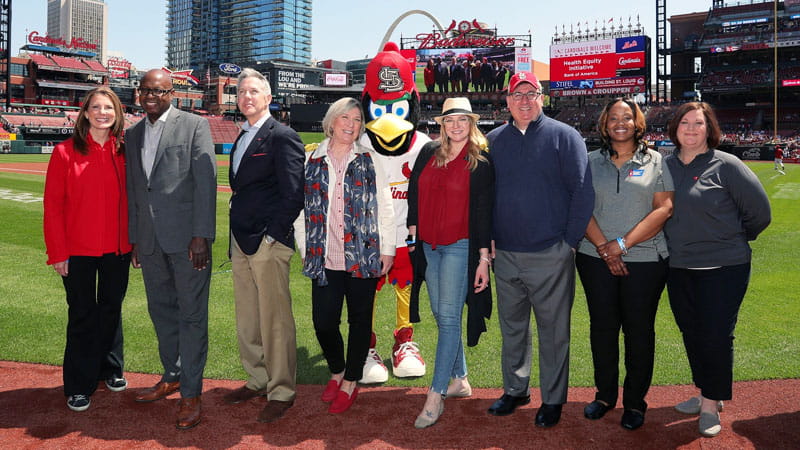 Bank of America leaders, Marilyn K. Bush and Katie Fischer — on the field at a Cardinals game with representatives from the American Cancer Society, the American Diabetes Association and the AHA — mark the launch in St. Louis of a joint initiative to drive health equity. St. Louis is one of 11 cities the initiative encompasses. (Photo courtesy of Bank of America)