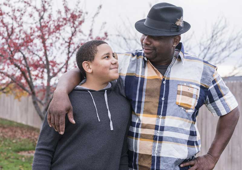 Black man and son arm in arm