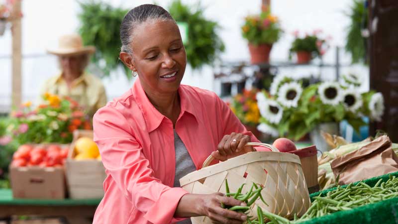 Una mujer eligiendo alimentos en un puesto de verduras