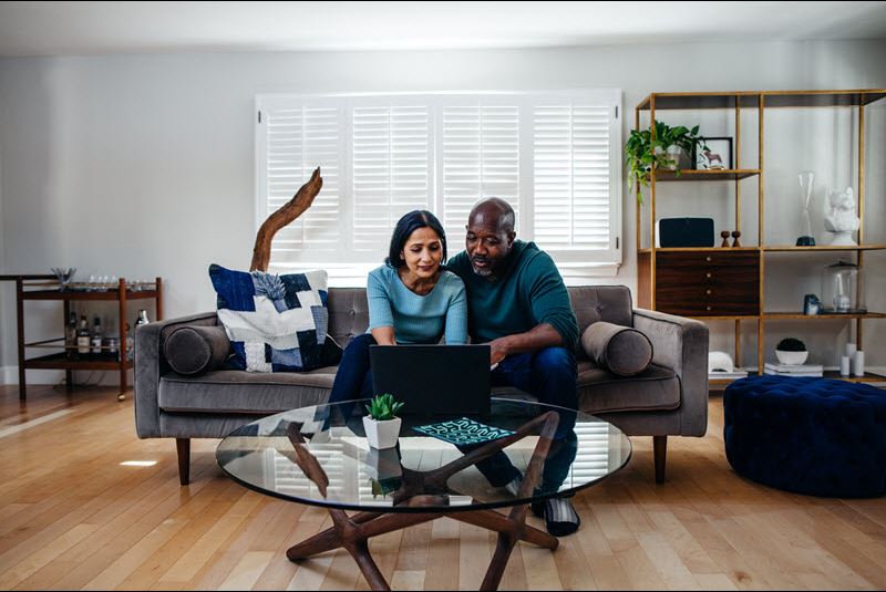 pareja sentada en el sofá usando la computadora