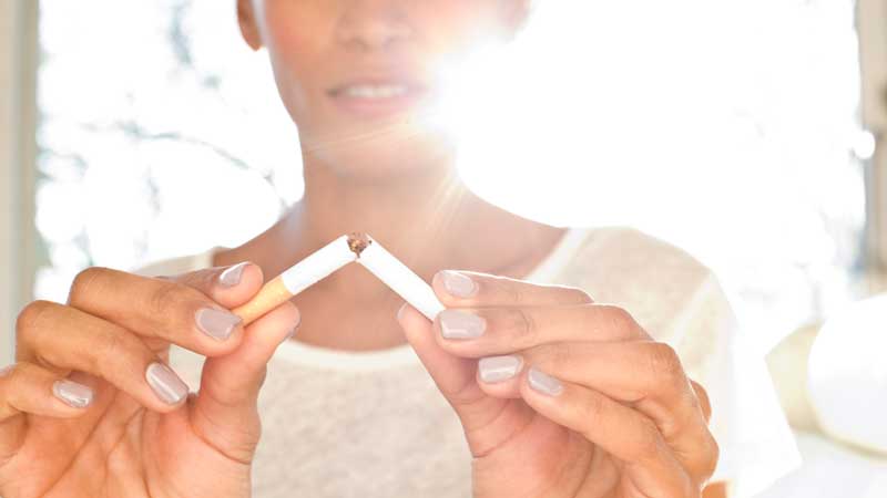 una mujer rompiendo un cigarrillo con las manos