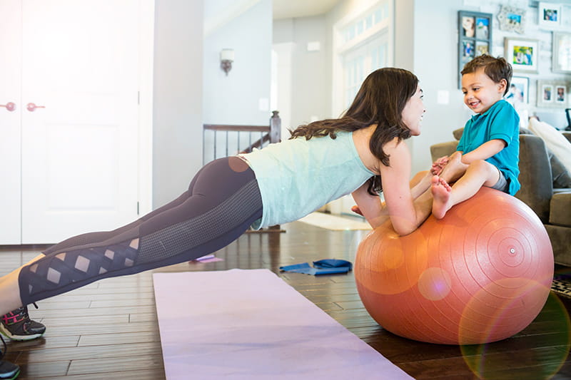 mamá equilibrando a su bebé en una pelota de yoga