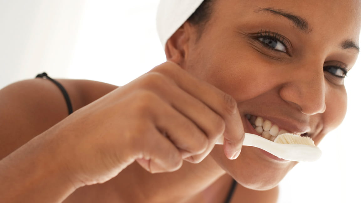 mujer joven cepillándose los dientes