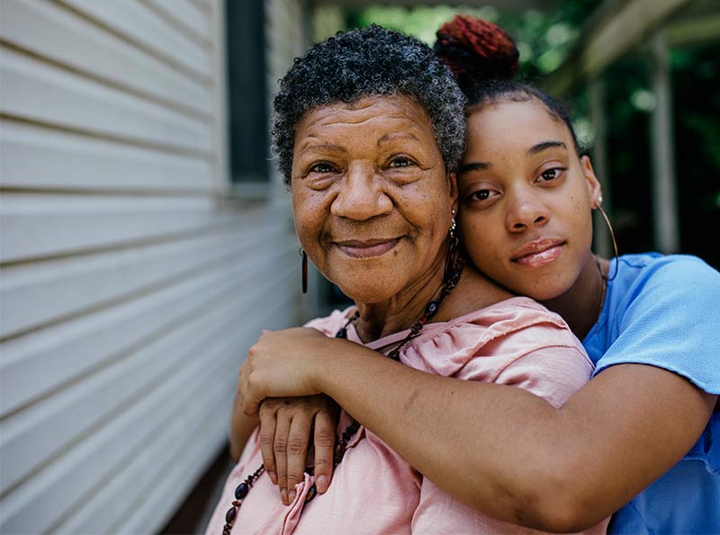 Una adolescente de raza negra abraza a su sonriente abuela