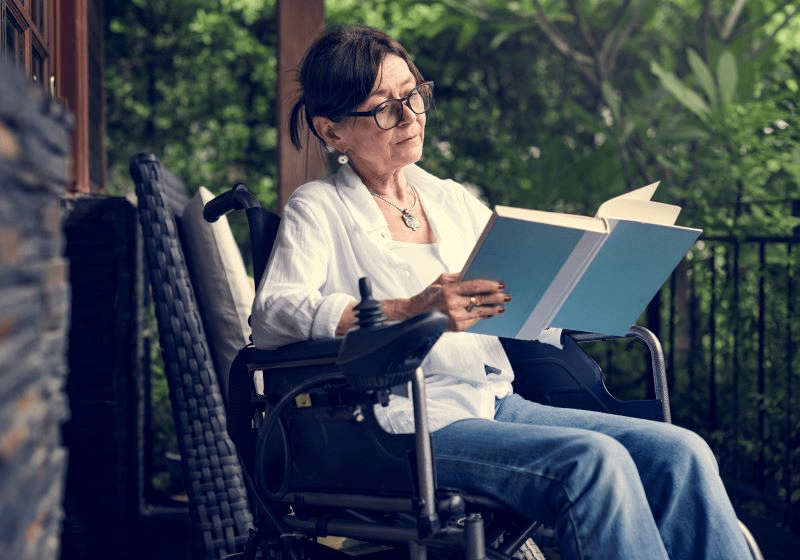 mujer sentada en una silla de ruedas leyendo un libro