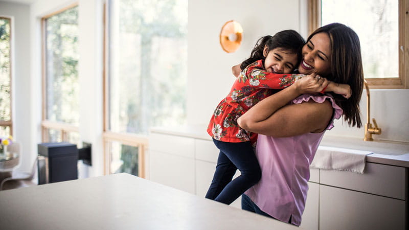 Mother and daughter embracing in the kitchen.