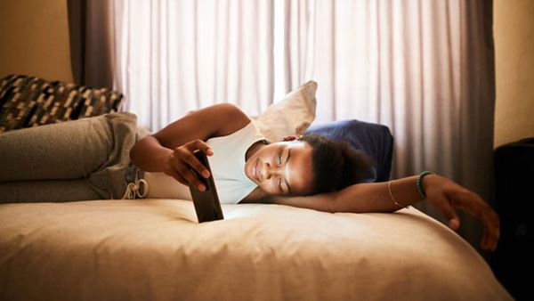 Teen in bed using her mobile phone.