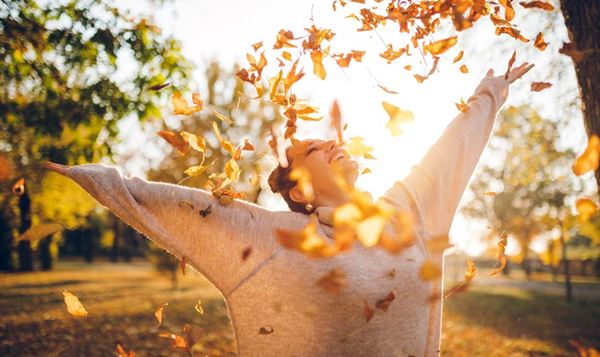 Woman playing in a park playing in the fall leaves