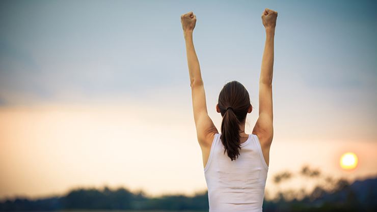 successful woman raising arms in triumph