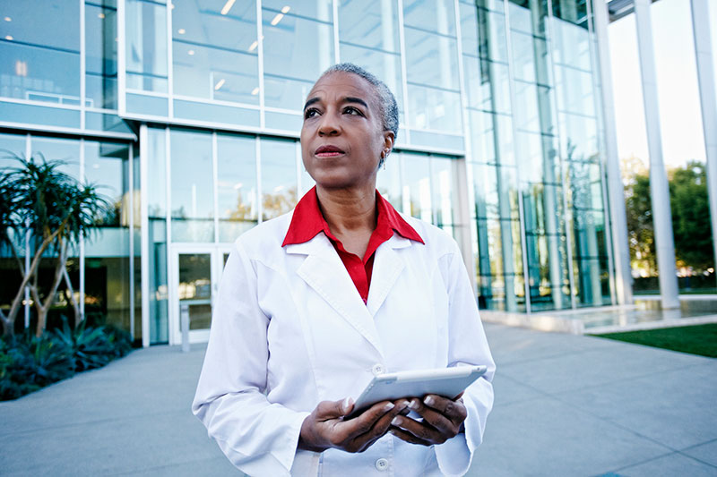 woman doctor or researcher holds tablet outside building GettyImages-738778729 woman doctor or researcher holds tablet outside building GettyImages-738778729