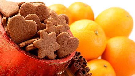 close up of gingerbread cookies, cinnamon sticks, and fresh oranges close up of gingerbread cookies, cinnamon sticks, and fresh oranges