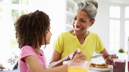 grandmother and granddaughter eating breakfast at the kitchen table grandmother and granddaughter eating breakfast at the kitchen table