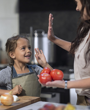 mom and daughter high-5 while cooking mom and daughter high-5 while cooking
