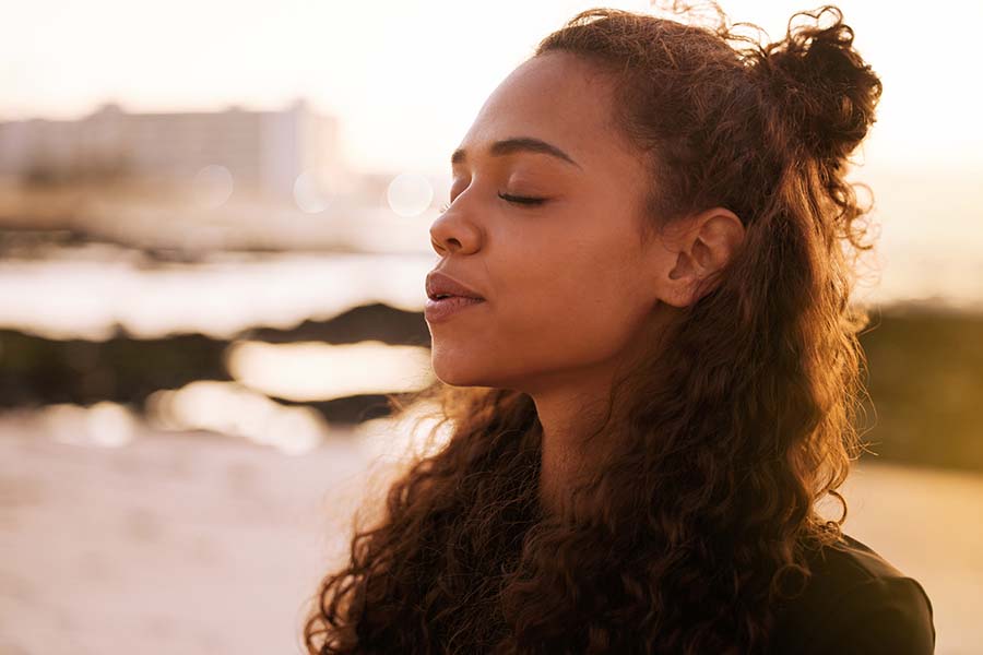 Primer plano de una mujer joven con los ojos cerrados, sintiendo el sol