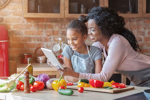 Mom and daughter read recipe on tablet while cooking GRFW logo