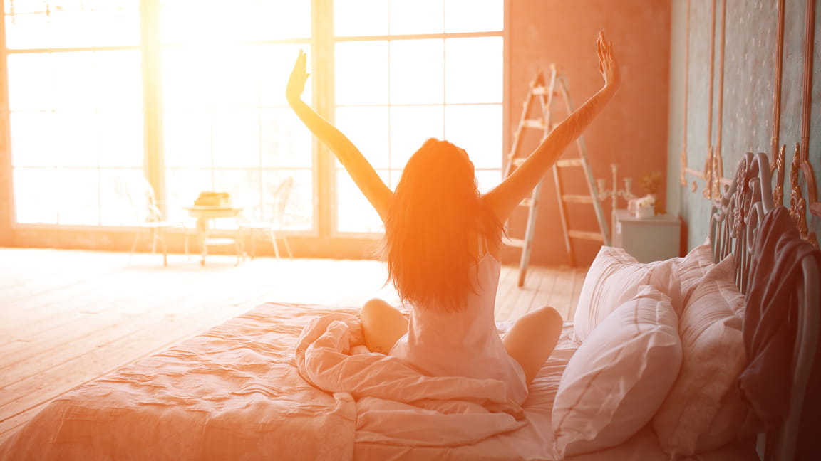 mujer estirándose antes de levantarse de la cama al amanecer