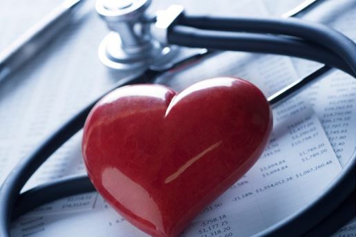 stethoscope and red stone heart laying on top of spreadsheets