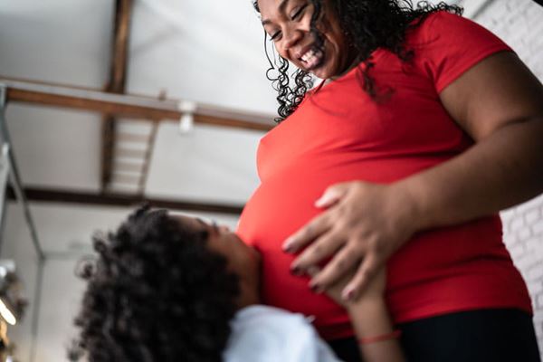 pregnant mother smiling down at her son